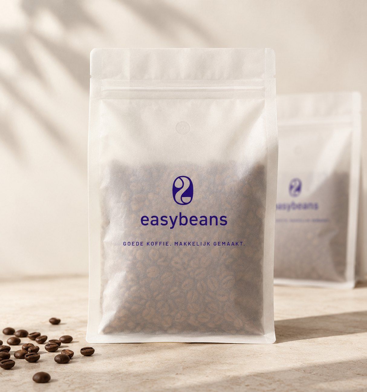 Matte transparante zak easybeans vol koffiebonen op een stenen blad, met losse bonen en bladschaduw